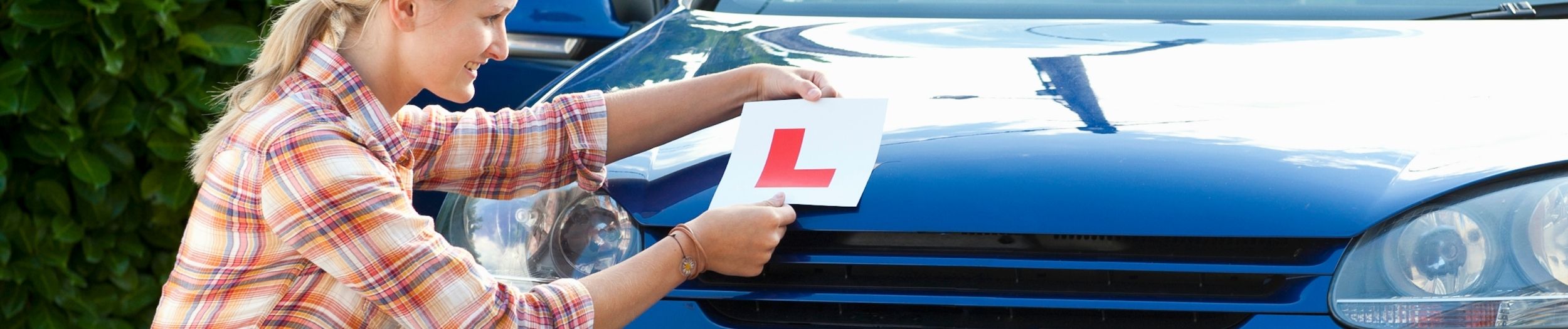Young girl putting learner badge on car