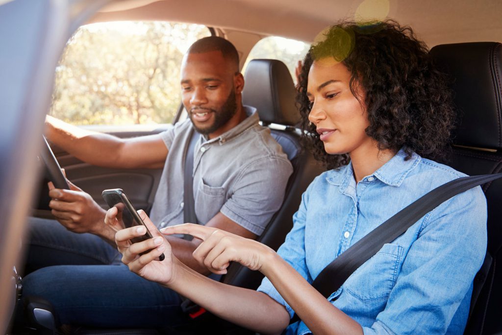 Couple sat in the car looking at a mobile