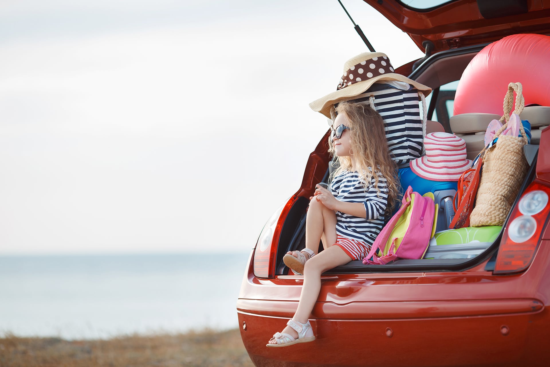 child sat on the boot of car